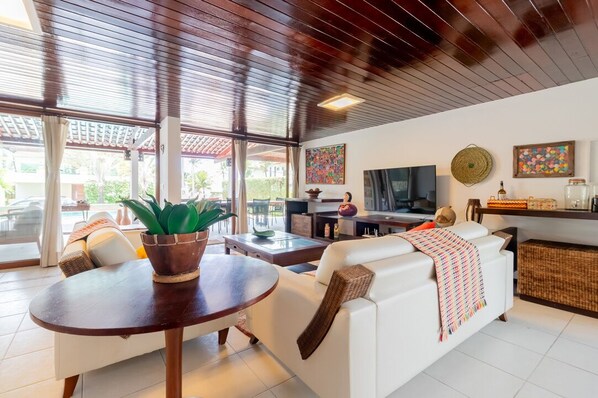 A modern living room with a white sofa, a round wooden table, and a TV.
