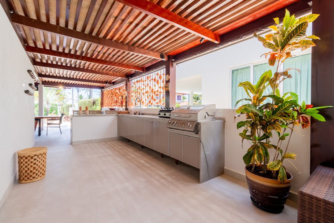 A modern kitchen with a wooden ceiling, grey cabinets, and a large potted plant.