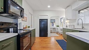 A modern kitchen with a built-in oven, microwave, and sink. There is a dining area with a table and chairs. - Whitetail Bungalow | Walk to Downtown Nampa | King Bed (Nampa)