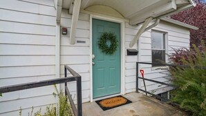 A house with a teal door, a welcome mat, and a mailbox. - Whitetail Bungalow | Walk to Downtown Nampa | King Bed (Nampa)