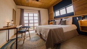 Un dormitorio con cama, escritorio, silla y un amplio ventanal.