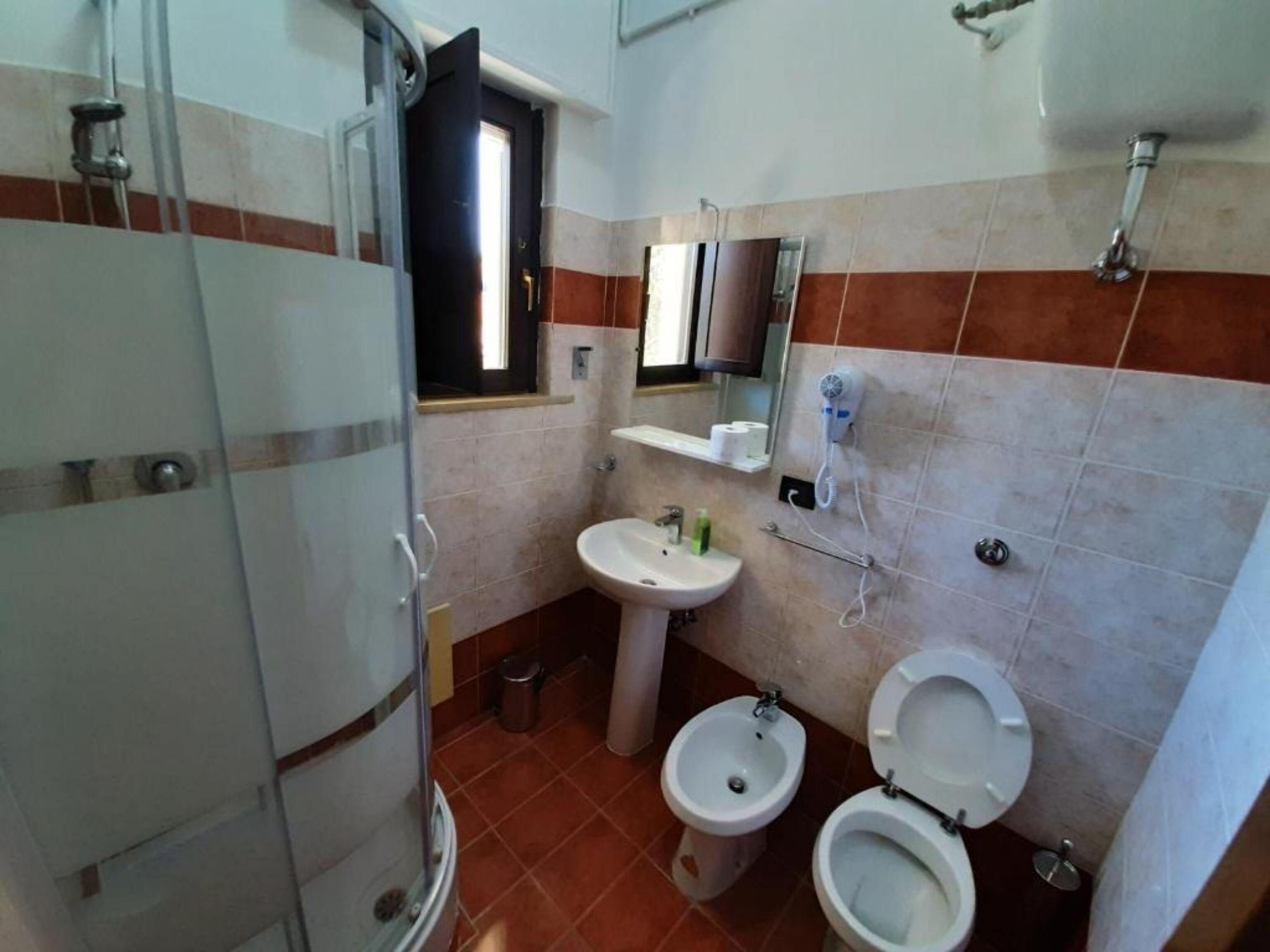 A bathroom with a shower, a sink, a bidet, and a toilet.