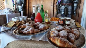 Una mesa con pasteles y condimentos, rodeada de estatuas de armaduras medievales.