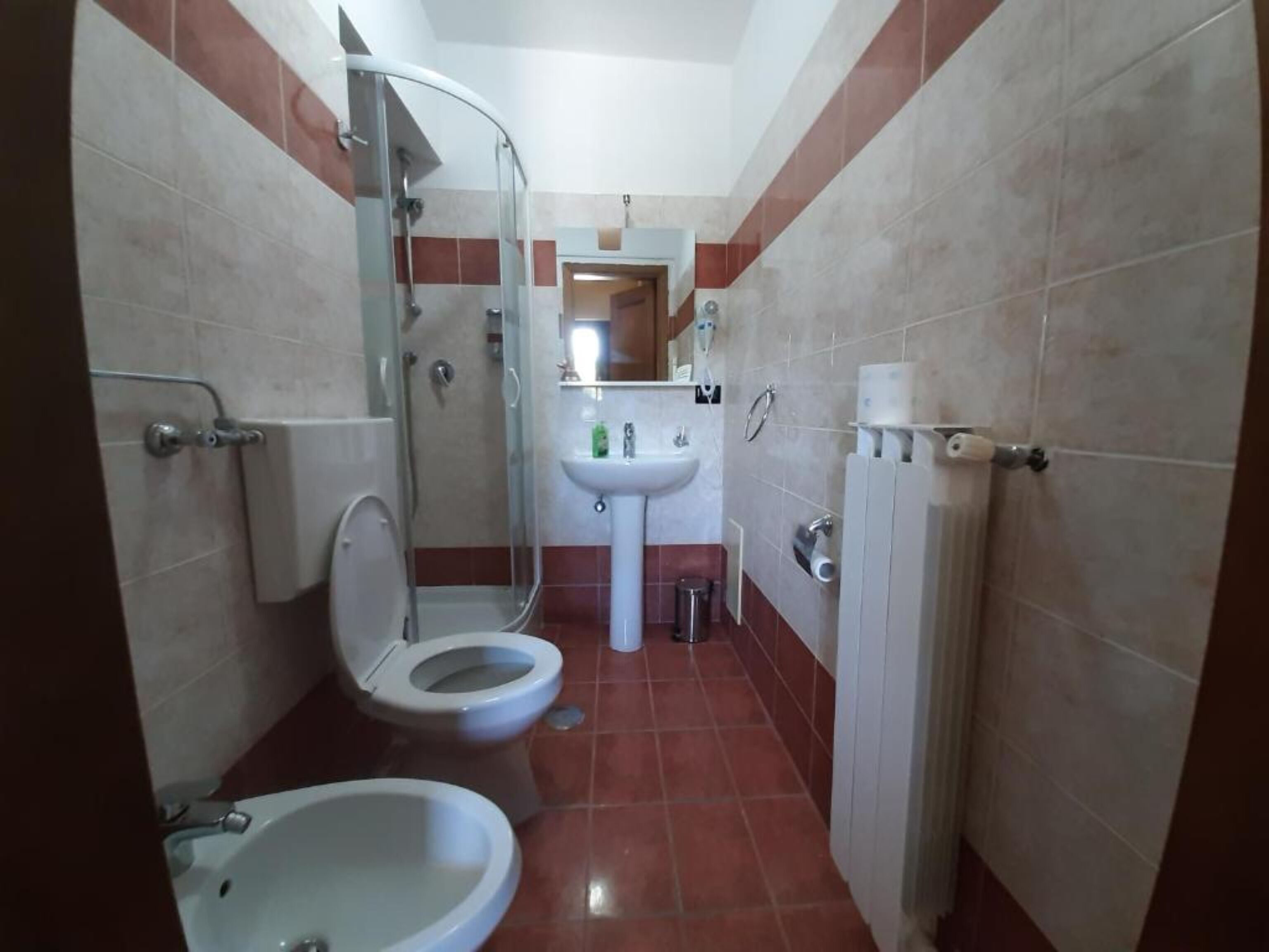 Un baño pequeño con ducha, inodoro y lavamanos.