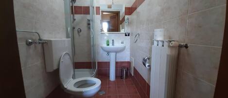 A compact bathroom with a shower, toilet, and sink.