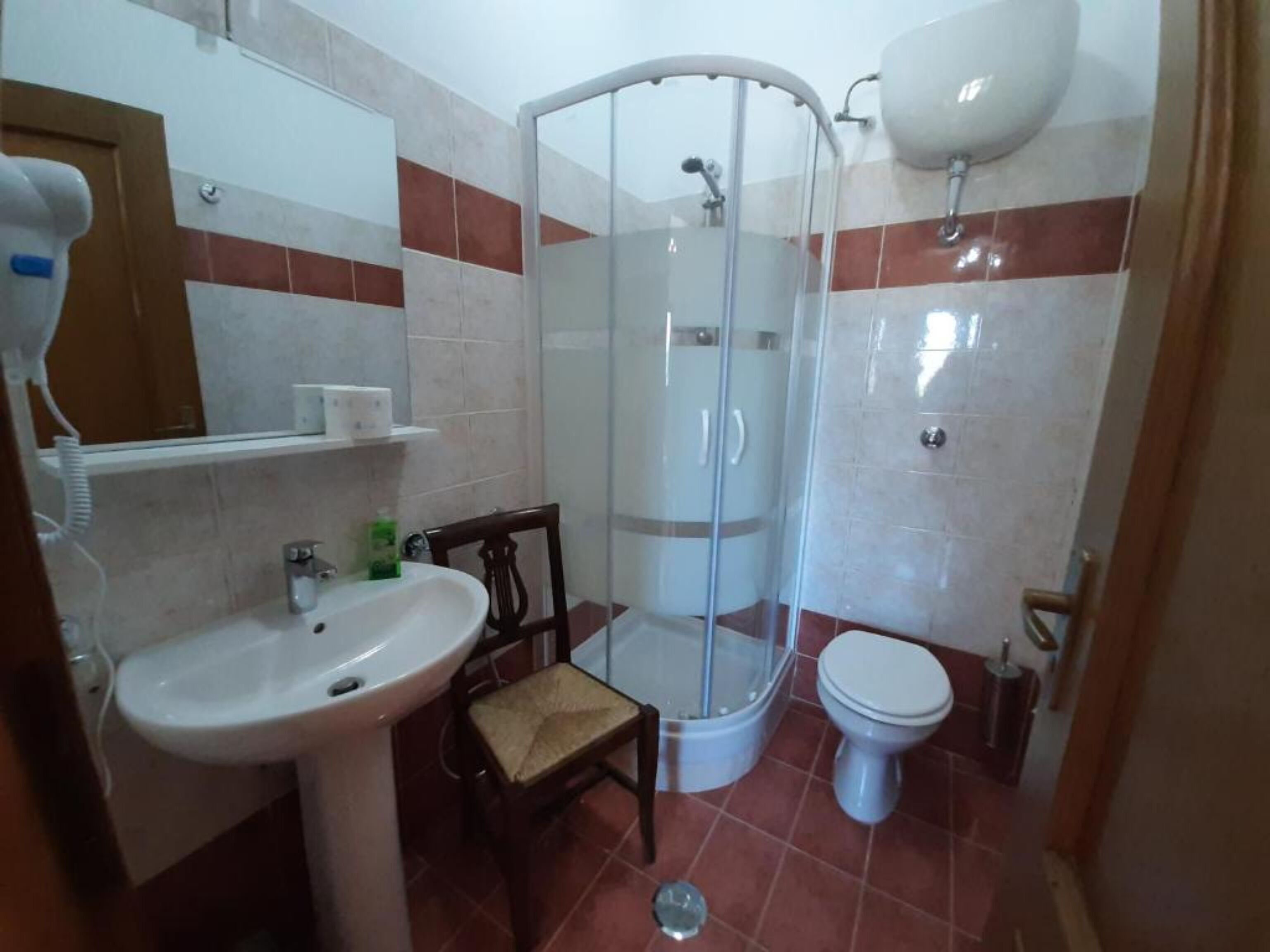 Un baño con ducha, inodoro, lavamanos y una silla.