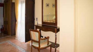 Una habitación con escritorio de madera, una silla, un espejo y una puerta.