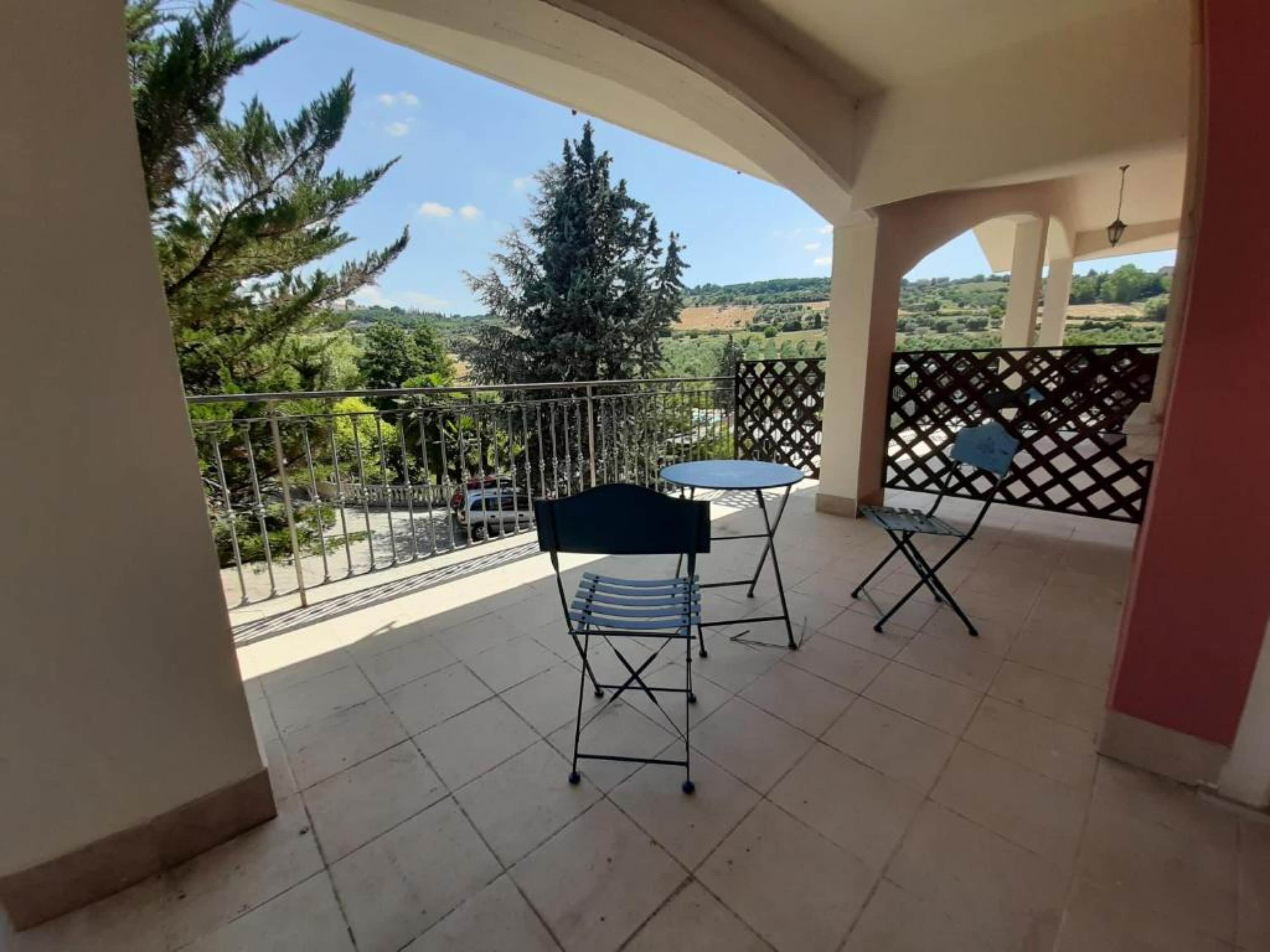 Ein Balkon mit Blick auf einen Baum und eine entfernte Landschaft.