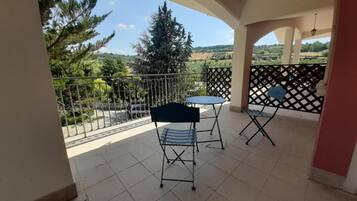 Ein Balkon mit Blick auf einen Baum und eine entfernte Landschaft.