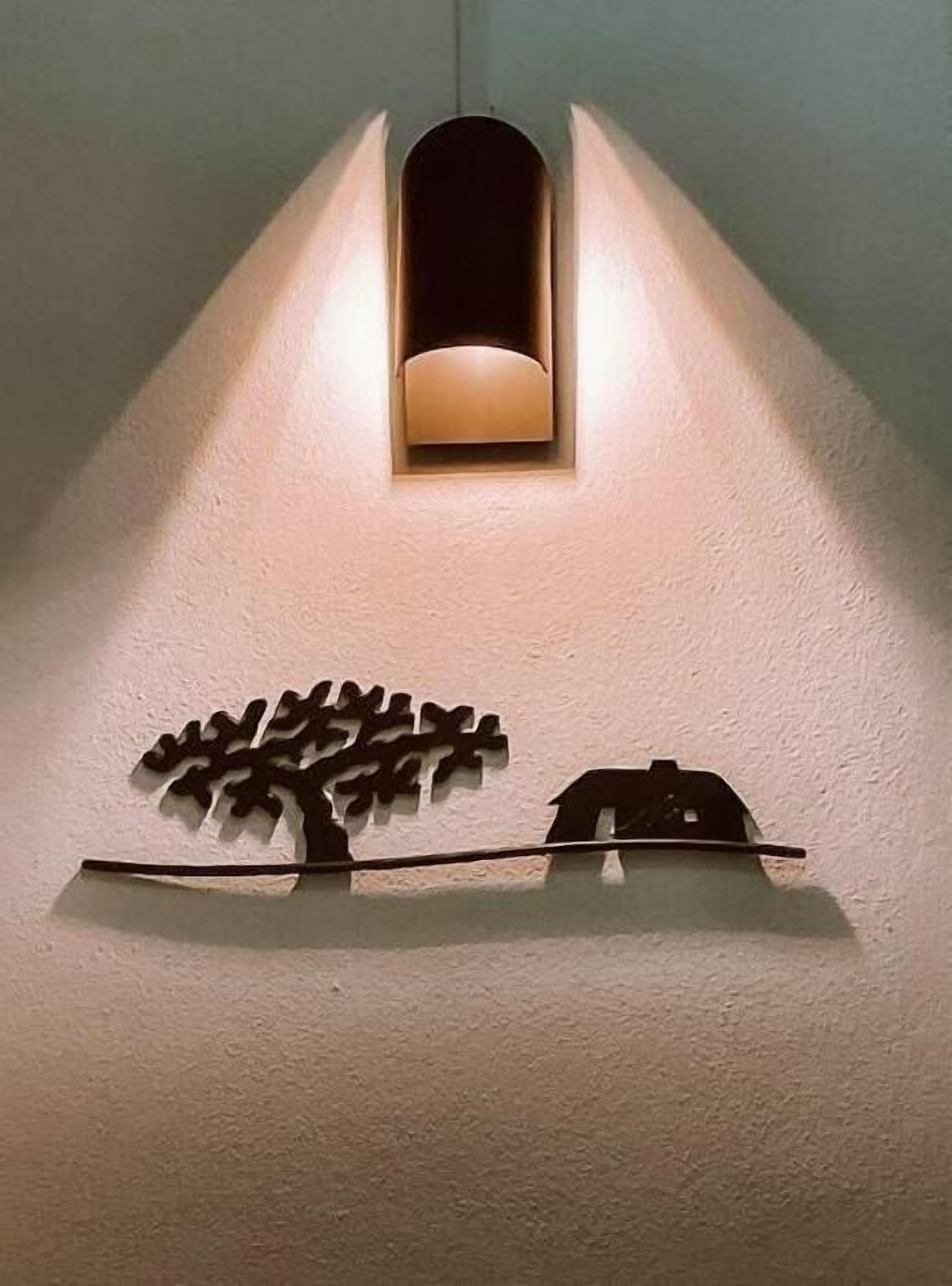 Eine Wandleuchte mit der Silhouette eines Baumes und eines Fahrzeugs.