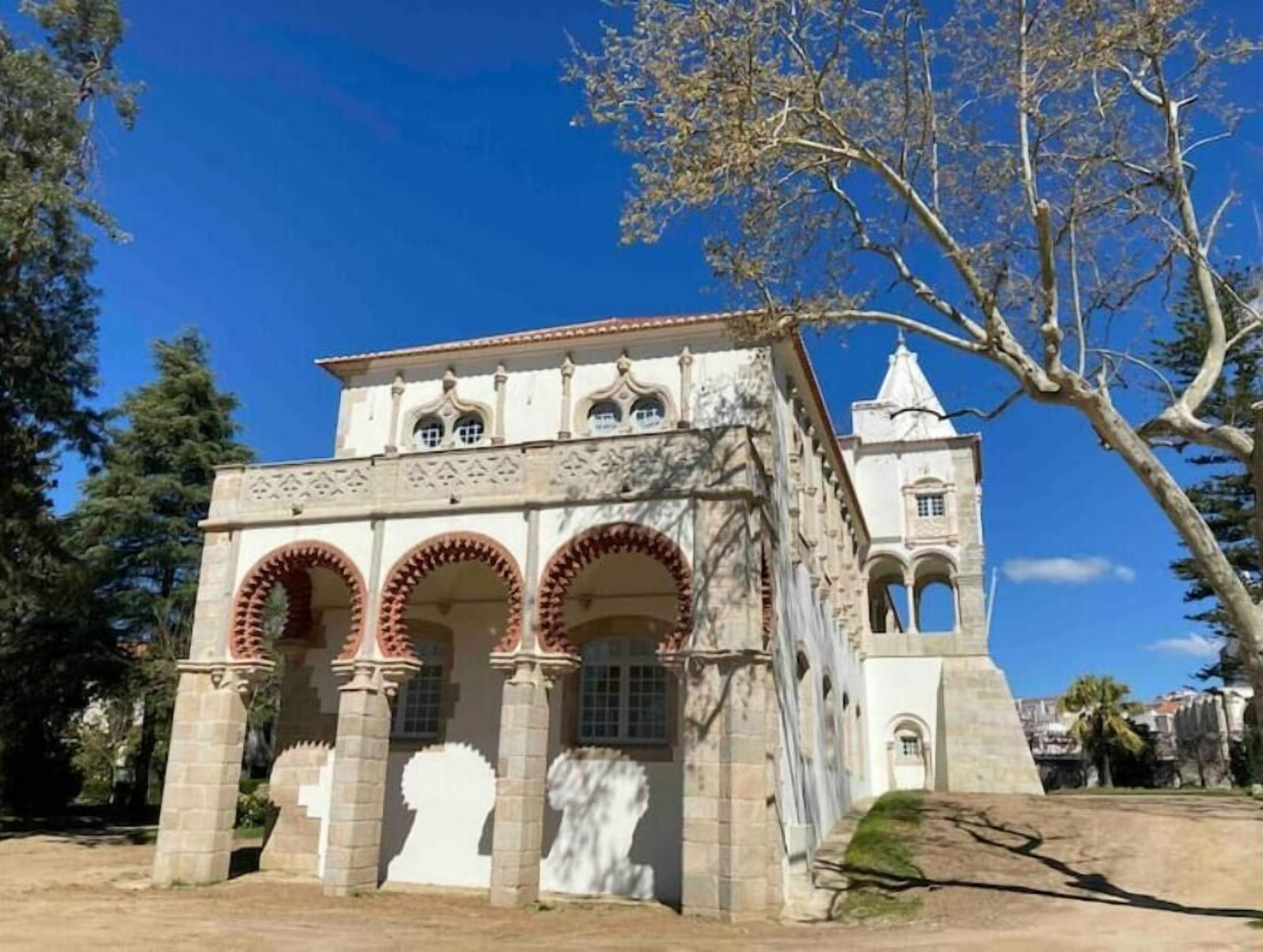 Un edificio histórico con una torre, ventanas de arco y un patio.