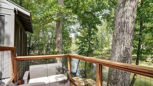 A wooden deck with wicker furniture overlooking a forested area. - Sunny Creekside Getaway (Cosby)