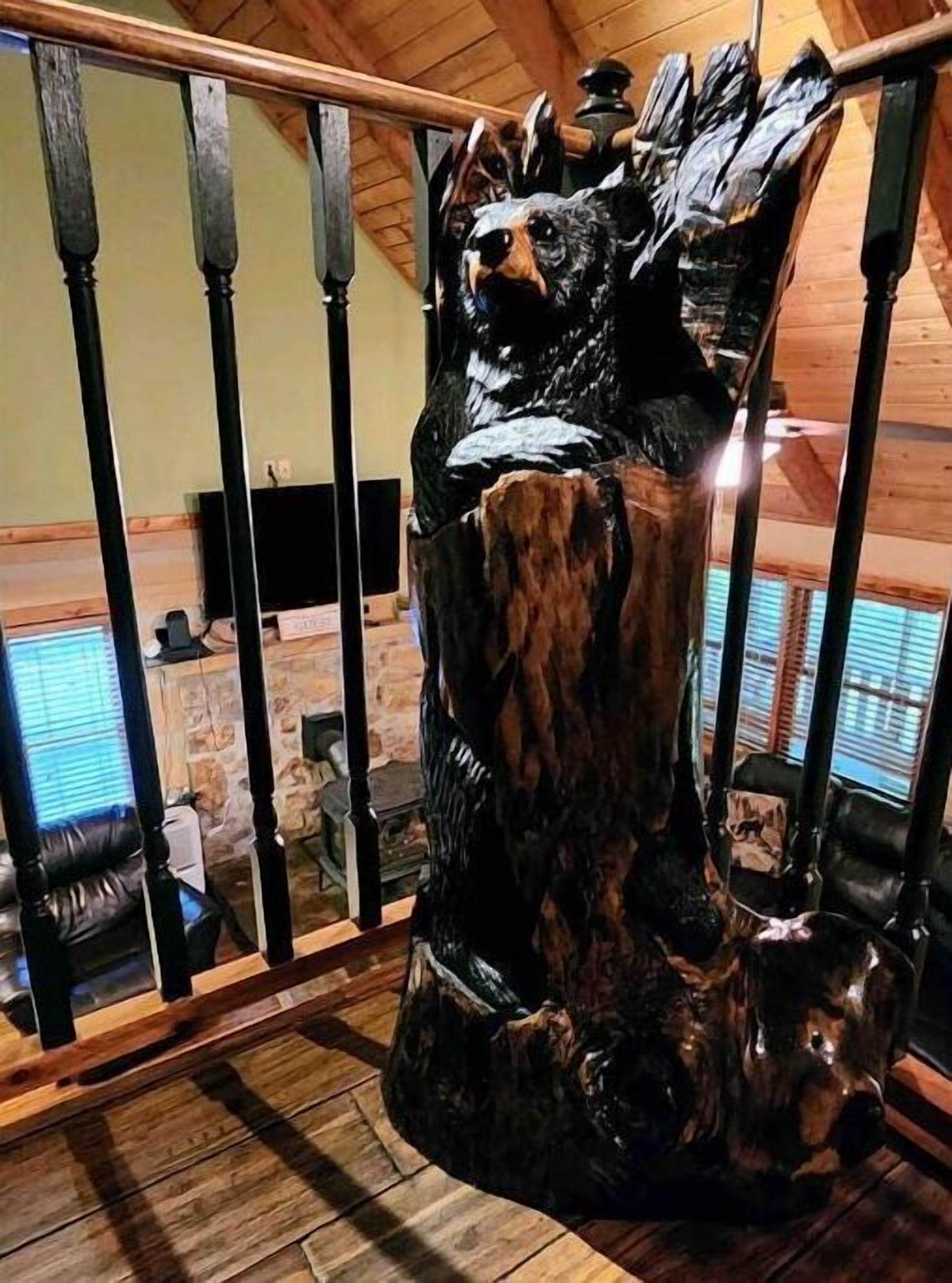 A wooden sculpture of a bear on a staircase railing.
