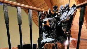 Une sculpture en bois représentant un ours, placée sur la rambarde d’un escalier.