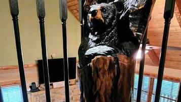 A wooden sculpture of a bear on a staircase railing.