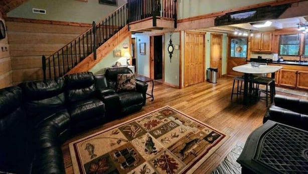 Un vaste salon agrémenté d’un escalier en bois, d’un coin repas et d’une cuisine.