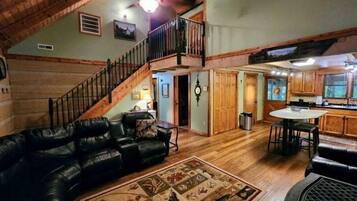 A spacious living room with a wooden staircase, a dining area, and a kitchen.