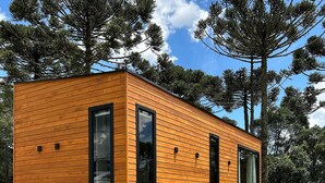 A modern wooden cabin with large windows, a bench, and a stone pathway. - Chalés Solar da Montanha Urubici (Urubici)