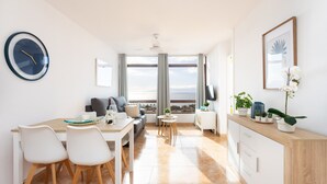 A modern living room with a dining area, large windows, and a view of the sea. - Playa La Arena with pool and privat parking (Santiago del Teide)