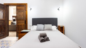 Un dormitorio con una cama grande, una puerta de madera y una mesita de noche pequeña.