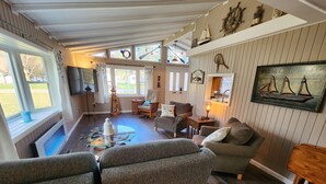 Un salon chaleureux avec une cheminée, un téléviseur et une décoration sur le thème de la mer.