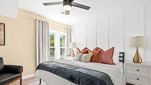A bedroom with a bed, nightstands, a chair, and a ceiling fan.