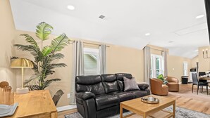 A modern living room with a leather sofa, wooden coffee table, and a dining area with a table and chairs.
