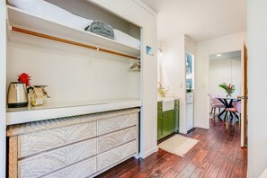 Een moderne keuken met witte kastjes, een houten vloer en een eethoek met een tafel en stoelen.
