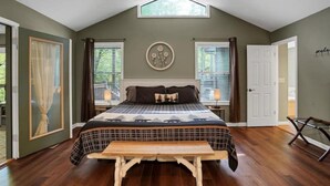 Un dormitorio con cama, una banca, una ventana y una puerta.