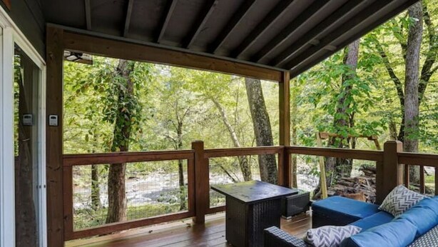 Una terraza techada al aire libre con barandilla de madera, un sofá y una mesa.