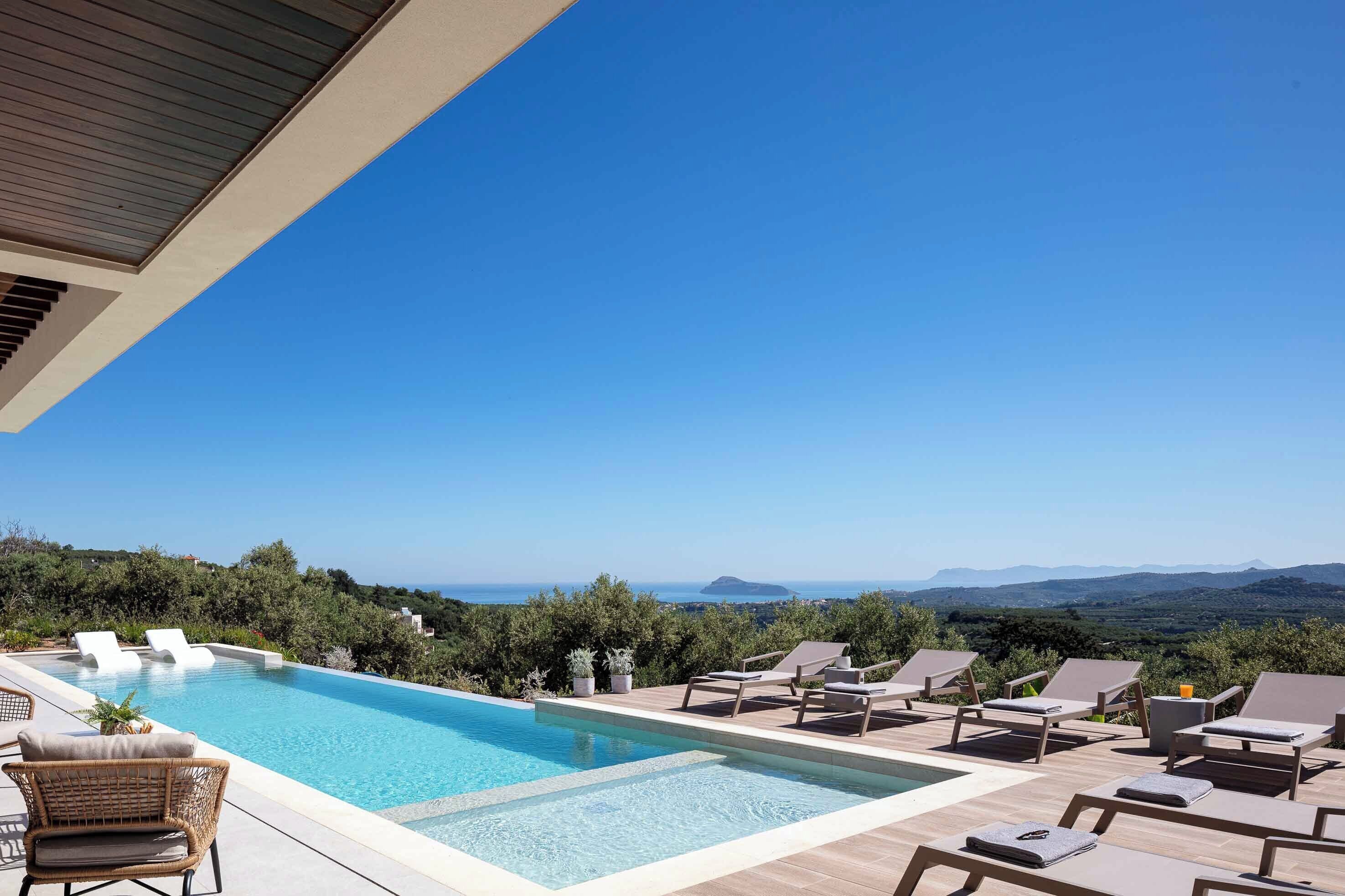 A pool area with lounge chairs and a view of the landscape.