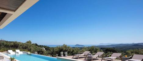 A pool area with lounge chairs and a view of the landscape.