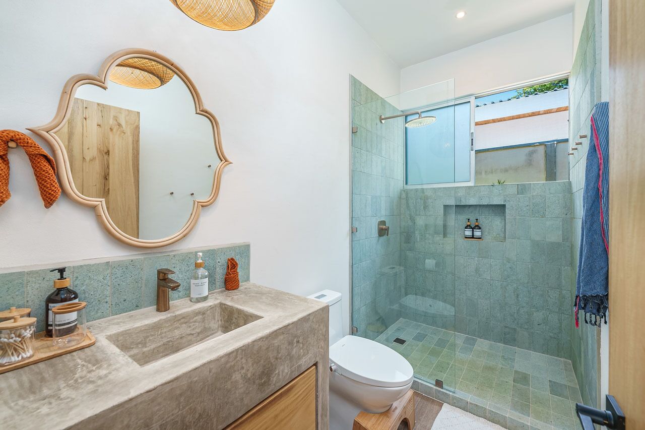 Een moderne badkamer met een grote spiegel, een wastafel met toiletartikelen en een douchecabine van glas.