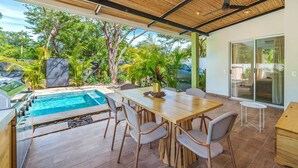 Eine moderne Außenpatio mit Pool, Essbereich und überdachter Sitzgelegenheit.