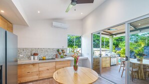 Eine moderne Küche mit einem runden Holztisch, einem eingebauten Herd und Blick auf die Terrassensitzgruppe.
