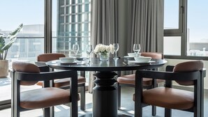 A dining area with a round table, six chairs, and a vase of white flowers. - Fraser Suites AL Liwan (Hamala)