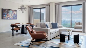 A modern living room with a sofa, armchairs, a dining table, and a large window with a city view. - Fraser Suites AL Liwan (Hamala)