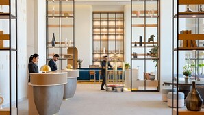 A modern hotel lobby with reception desks, seating areas, and decorative shelves. - Fraser Suites AL Liwan (Hamala)