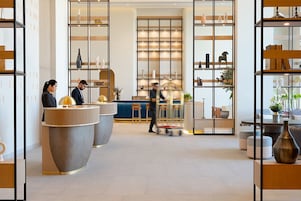 Un moderno vestíbulo de hotel con mostradores de recepción, zonas de estar y estanterías decorativas.