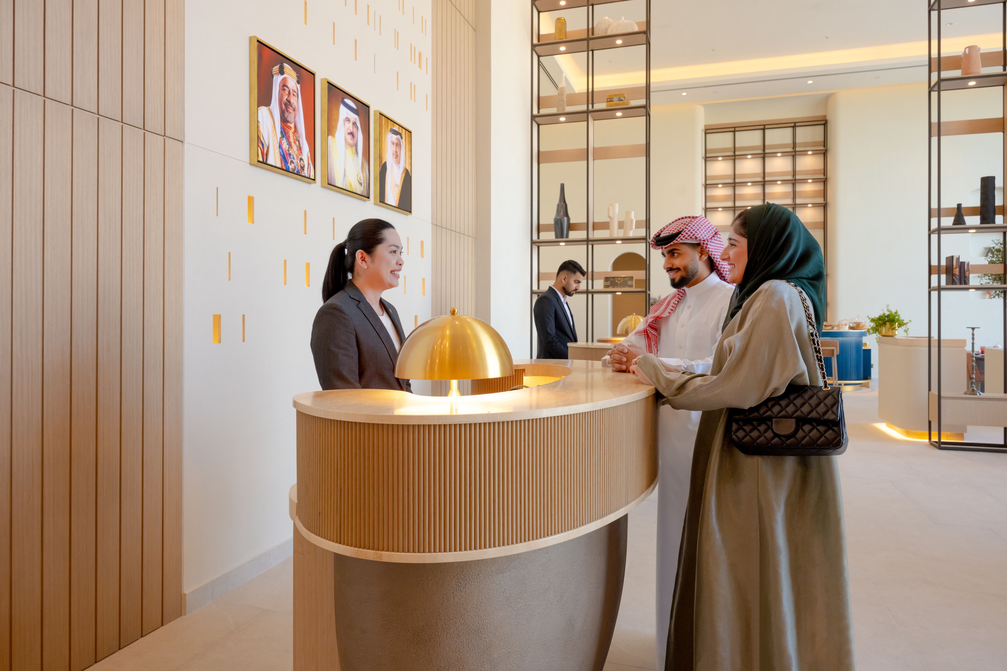 A reception desk with a modern design, a large gold lamp, and framed pictures on the wall.