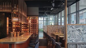 A restaurant interior with a bar area, seating, and patterned walls. - 21 Carpenter, Singapore, a Member of Design Hotels (Singapore)