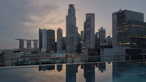 A city skyline reflected in a still body of water, featuring modern high-rise buildings. - 21 Carpenter, Singapore, a Member of Design Hotels (Singapore)