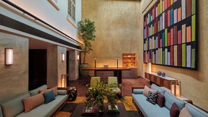 A spacious lobby with a high ceiling, a central seating area with sofas and chairs, a large bookshelf, and a potted plant. - 21 Carpenter, Singapore, a Member of Design Hotels (Singapore)