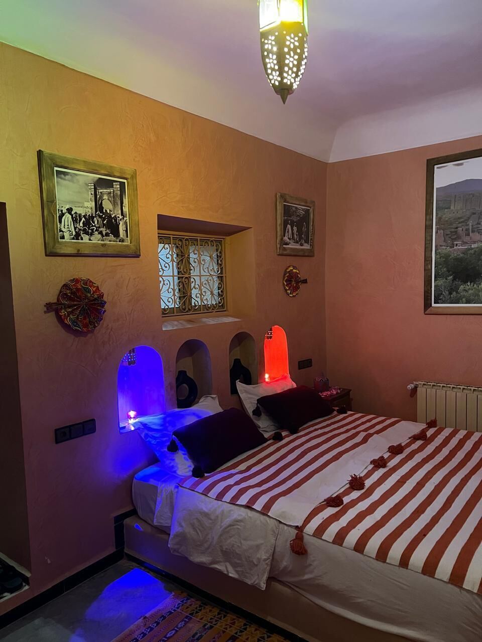 Une chambre à coucher avec un lit, une fenêtre et des éléments décoratifs sur les murs.
