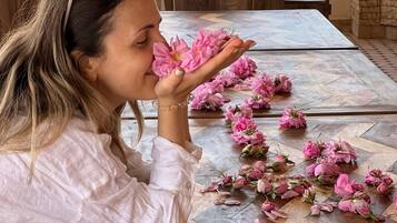 A dining table with a patterned tablecloth and scattered pink flowers.