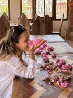 Una mesa de comedor con mantel estampado y flores rosadas dispersas.