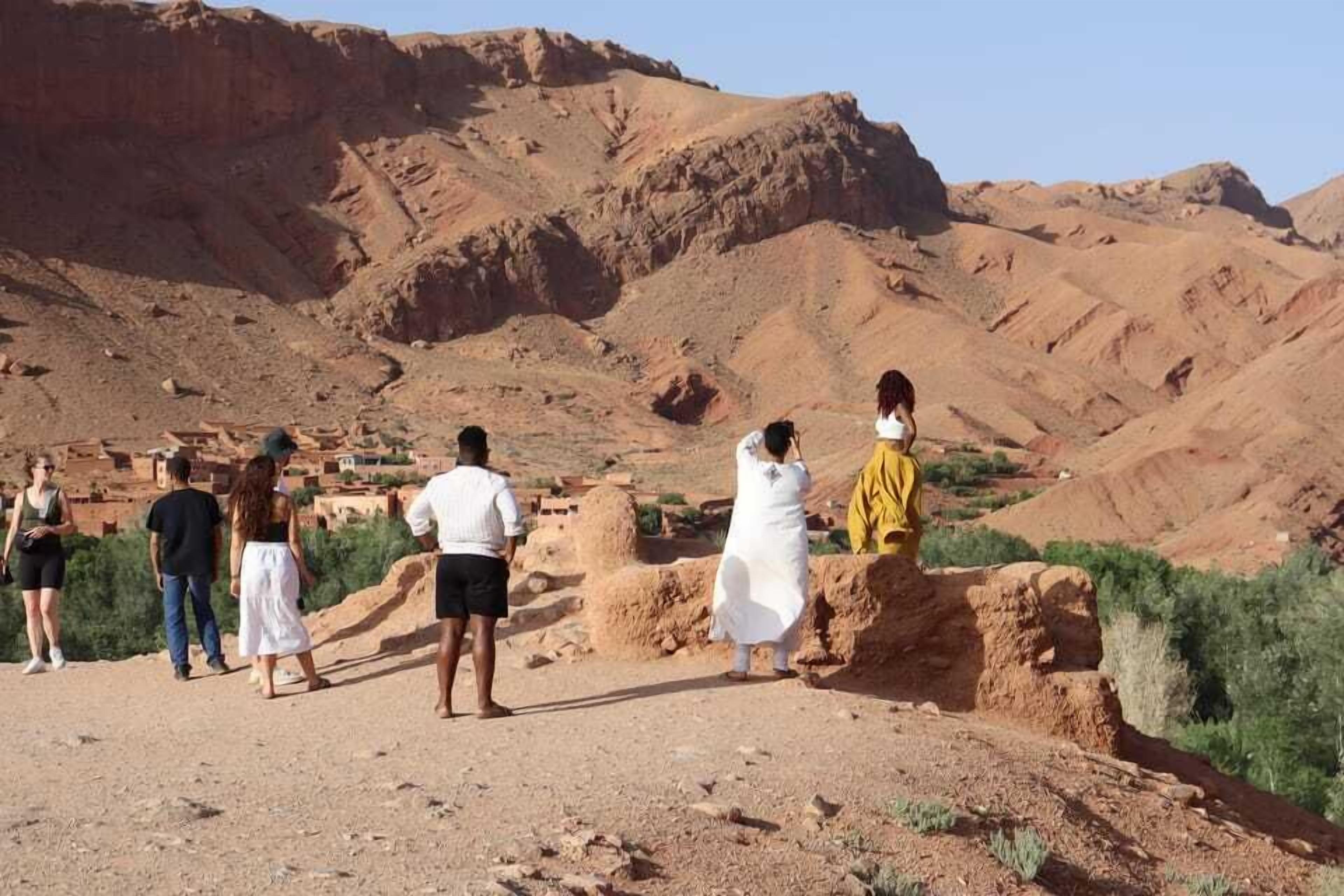 A group of people standing on a rocky terrain with a mountainous backdrop.