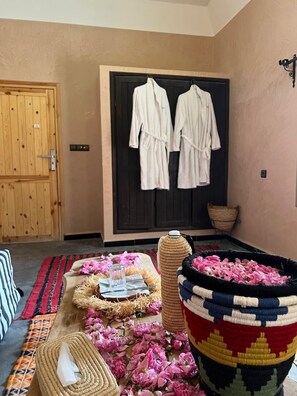 Ein Zimmer mit Holztür, einem spiegel mit schwarzem Rahmen, einem gewebten Korb mit rosa Blumen und einer gewebten Matte auf dem Boden.