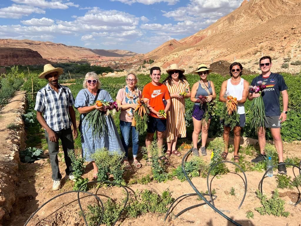 A group of people standing in a garden with plants and hoses.