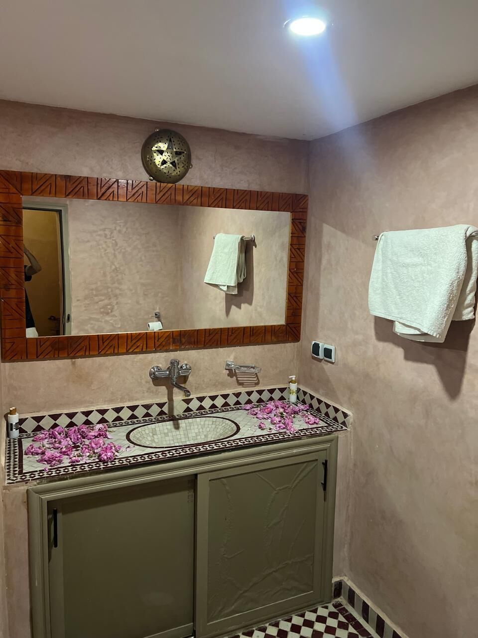 A bathroom with a mirror, two sinks, a clock, and towels on the wall.